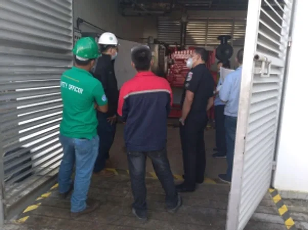 Group of workers in hard hats at the louvered door of an equipment room