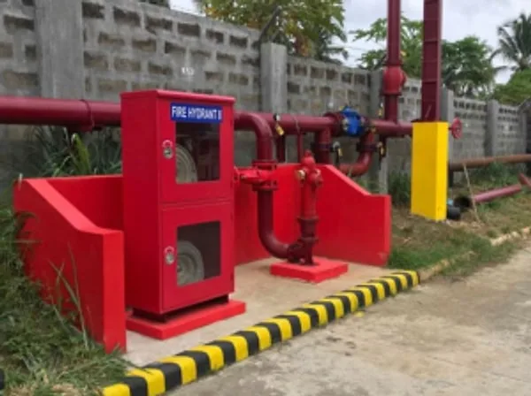 Red fire hydrant cabinet and hydrant piping beside a perimeter wall