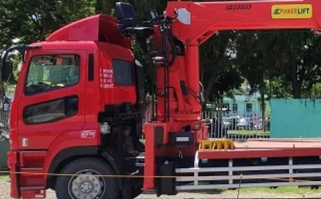 Red boom truck with a telescopic crane parked on a roadside