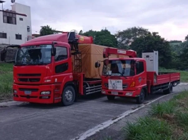 Two red boom trucks parked on a road