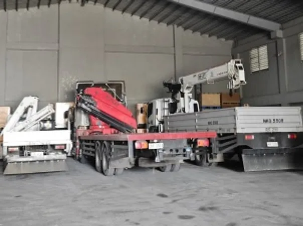 Boom trucks with folded knuckle cranes parked inside a warehouse