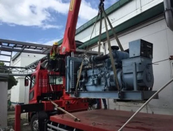 Boom truck lifting a blue diesel engine generator set with slings