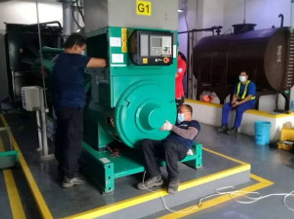 Technicians in masks working on a green generator alternator