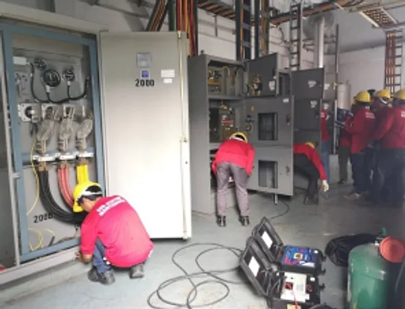 Team of technicians working at switchgear panels with test equipment on the floor