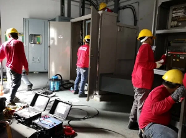 Technicians in hard hats testing switchgear with portable test instruments